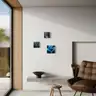 Three miniature paintings of nudes in cool tones hanging on a light wall