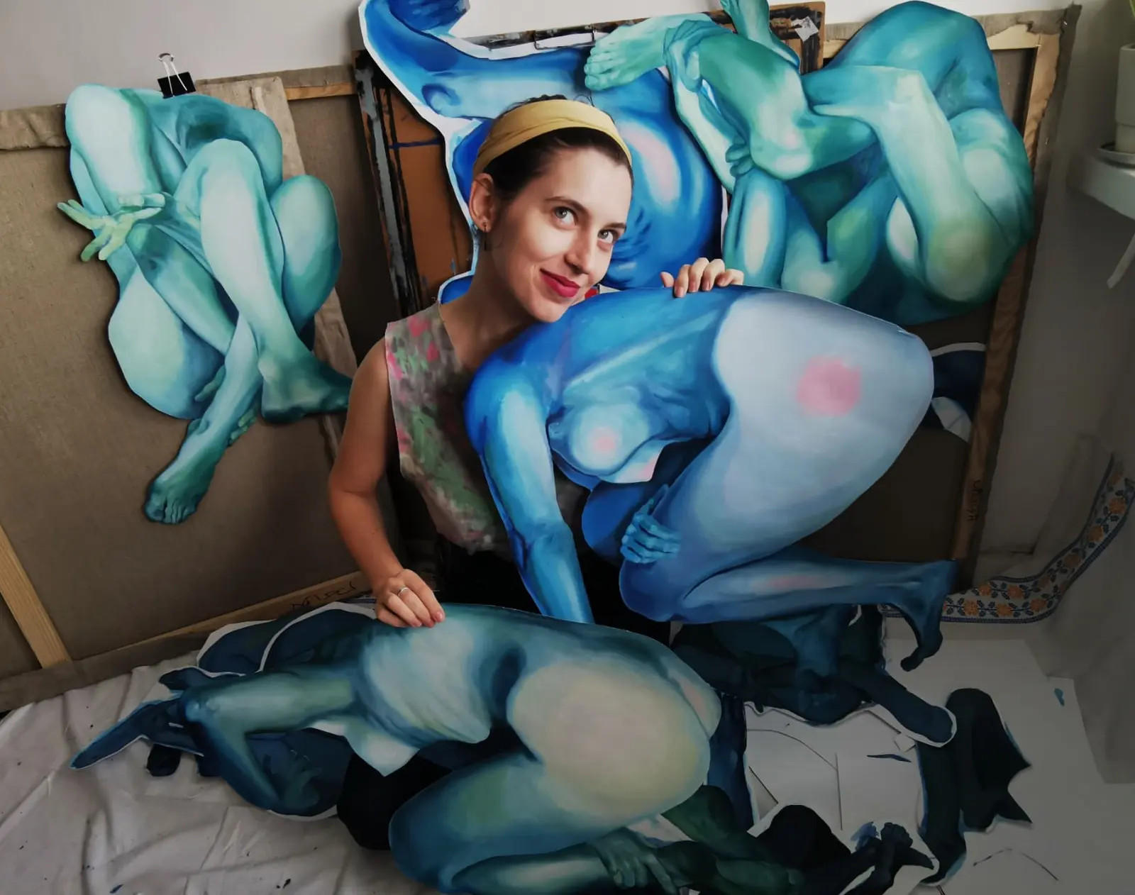 Artist posing with cut-out blue body silhouettes in the studio