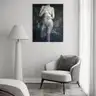 Modern female nude canvas painting hanging in a minimalist bedroom with a light armchair and neutral interior design
