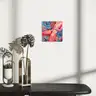 Visualization of a colorful contemporary painting depicting a nude body against abstract patterns, hung on a white wall above a console with decorations in a minimalist interior
