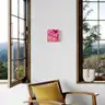 A pink-toned painting with female legs hanging on a wall by a large window