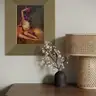 Modern interior with a painting depicting a female nude with purple leaves in a golden frame, placed above a sideboard with a lamp and flowers