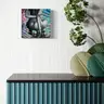 Painting of a female body on a colorful wave background above a blue cabinet with plants