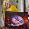 Artist presenting a nude painting with a galaxy background in violet-red hues