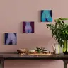 Interior visualization with three small paintings of female nudes from behind, hanging above a set table