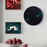 Paintings with female nudes in intense tones above a marble counter with red plums