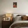 Bedroom in natural tones with a painting depicting a female nude with botanical elements above a bedside table with a lamp and vase