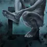 A male nude in a seated pose on a turquoise background with a geometric motif