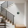 A contemporary home interior with wooden stairs and a black metal railing, featuring a round abstract illustration of an artistic male nude hanging on the wall