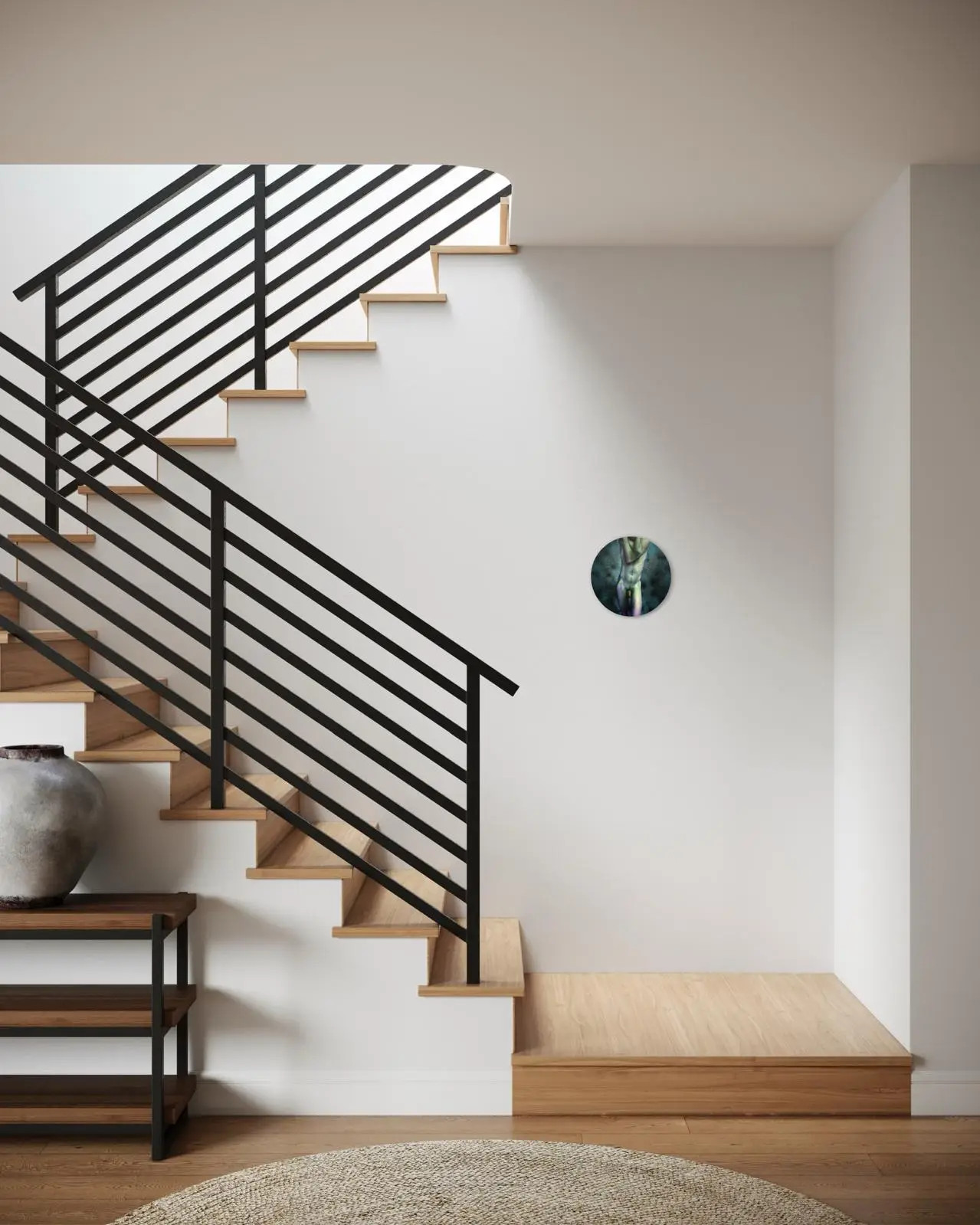 A contemporary home interior with wooden stairs and a black metal railing, featuring a round abstract illustration of an artistic male nude hanging on the wall