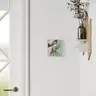 Visualization of a modern surrealist painting depicting a female body and a green hand, hung on a white wall next to a door and a shelf with a vase, minimalist interior decoration