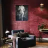 Modern female nude canvas painting displayed on a red brick wall in a stylish living room with a designer armchair