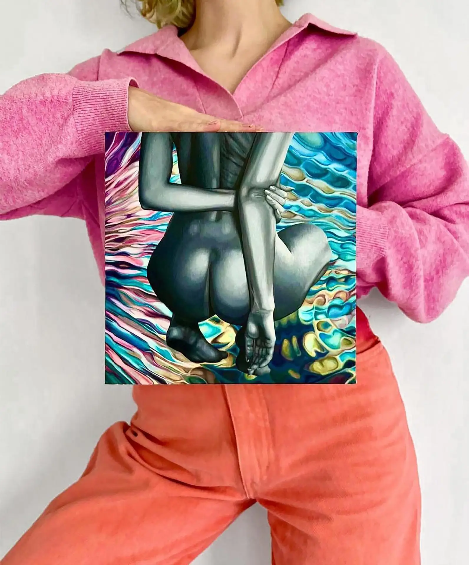 Painting of a female nude in gray tones on a colorful wave background held by a person in a pink sweater