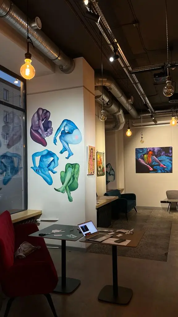 Wnętrze galerii z muralami przedstawiającymi kolorowe, splecione nagie postacie