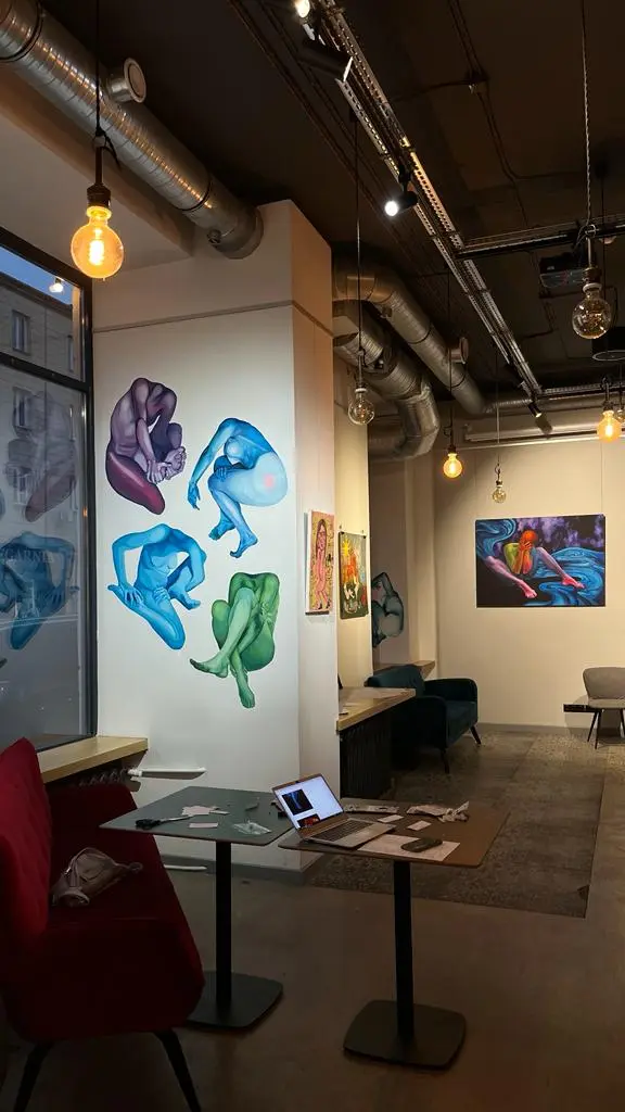 Wnętrze galerii z muralami przedstawiającymi kolorowe, splecione nagie postacie