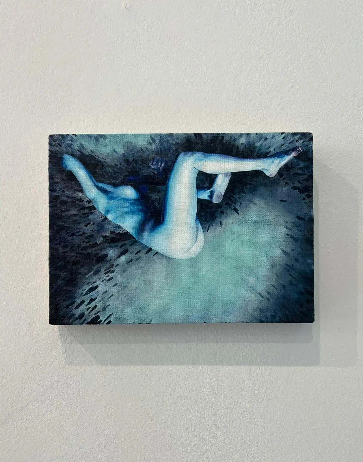Painting depicting a blue female nude in a dynamic pose, hanging on a light wall